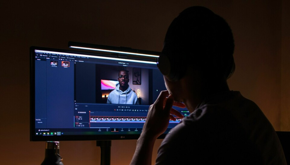 The rumors about YouTube's AI-alterations surfaced on Reddit in June. A person is sitting in a dark room, editing a YouTube video.