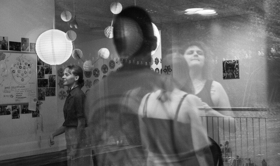 Portrait of four people. Three is reflected trough the window and a woman is inside the house.