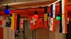 Row of international flags hanging indoors beneath colorful string lights.