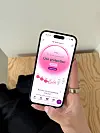 En hånd holder en smartphone med en fertilitetsapp på skærmen.
