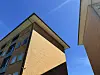 To boligblokke i gule og brune mursten ses nedefra mod blå himmel.