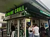 People queue outside a Gasoline Grill burger shop in a converted petrol station, with green signs above the entrance.