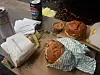 Two wrapped burgers with fries, dipping sauce and Pepsi cans on a table.