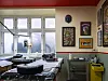 Tattoo station with equipment, framed artwork and large windows inside Yellow Dragon Tattoo studio in Aarhus.