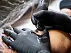 Gloved tattoo artist shading a client’s custom tattoo with a tattoo machine.