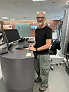 Kenneth står ved et skrivebord med computer på et moderne kontor.