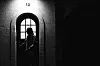 A silhouetted mail carrier stands behind the glass of an arched door marked 13.